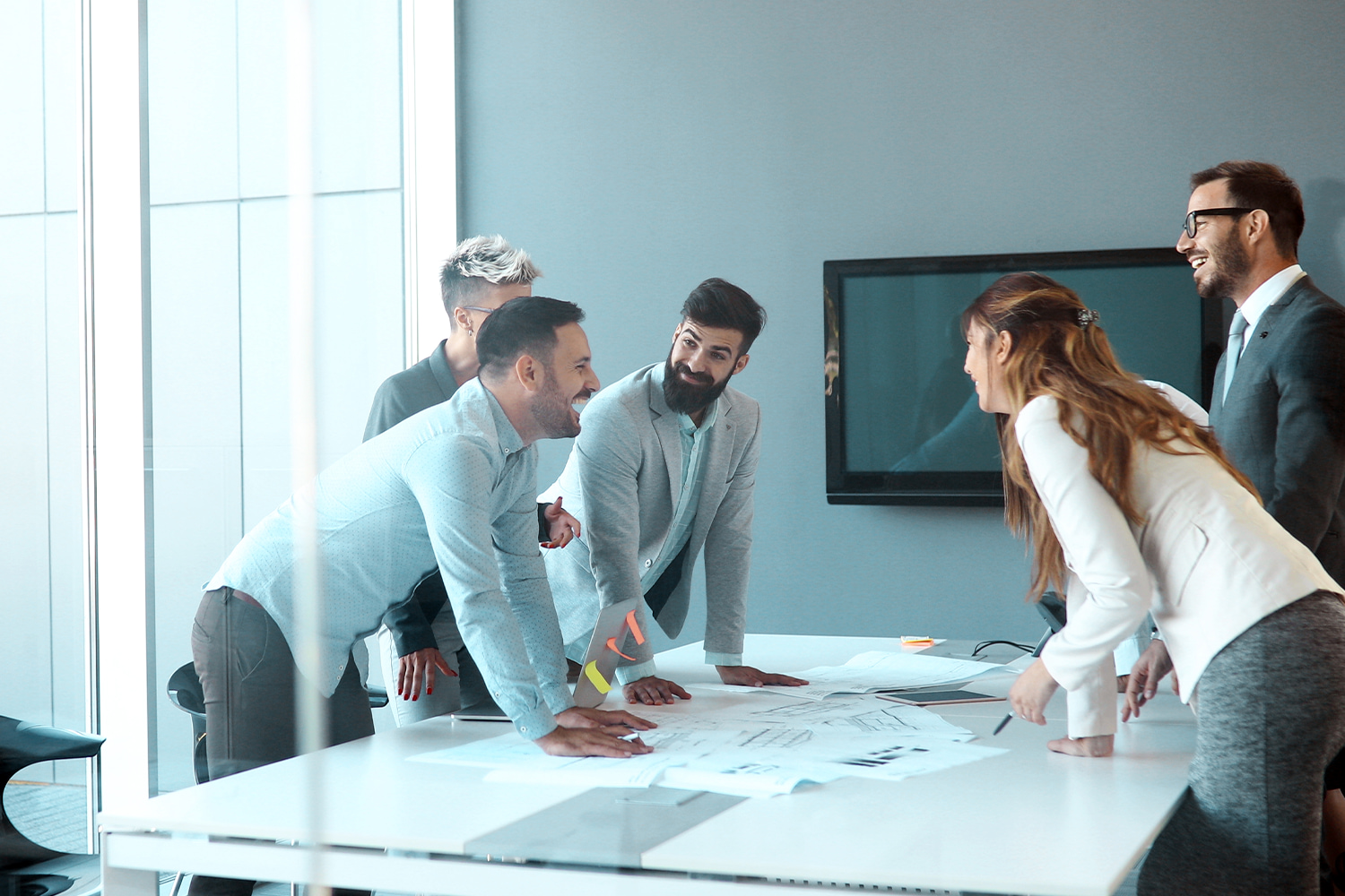 Professionals laughing over blueprints, showing the team culture at top employers in Utah.