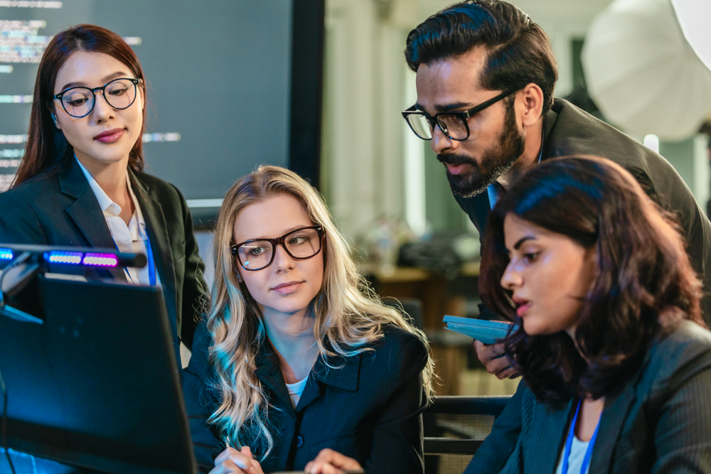 Diverse group of software engineers, featuring women and tech professionals, collaborating on complex code and development projects.