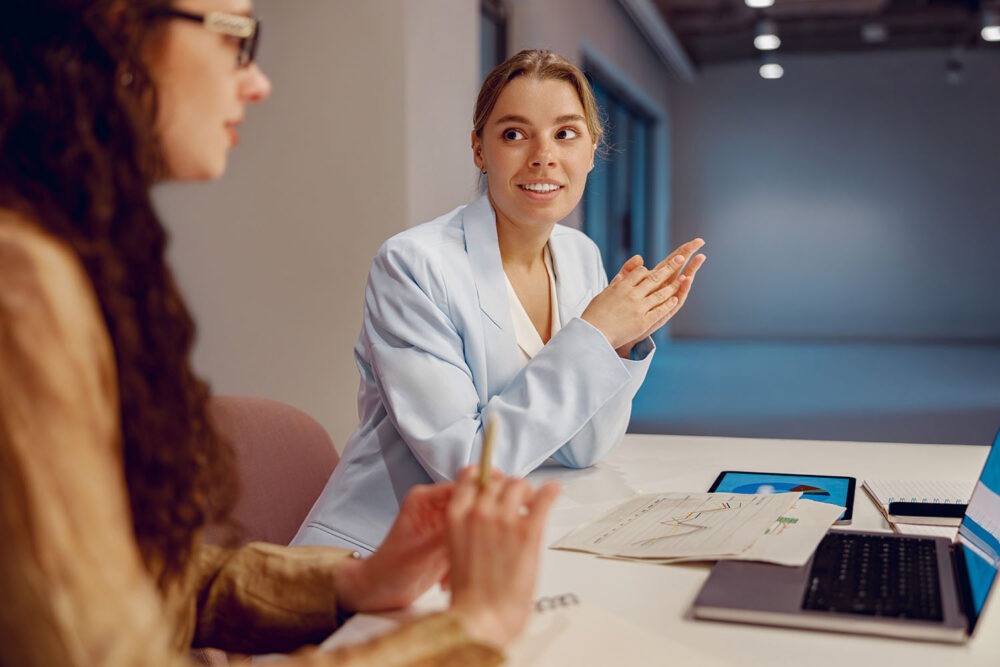Two professional women reviewing women in tech statistics on a laptop. Focused on data-driven retention strategies for tech women.