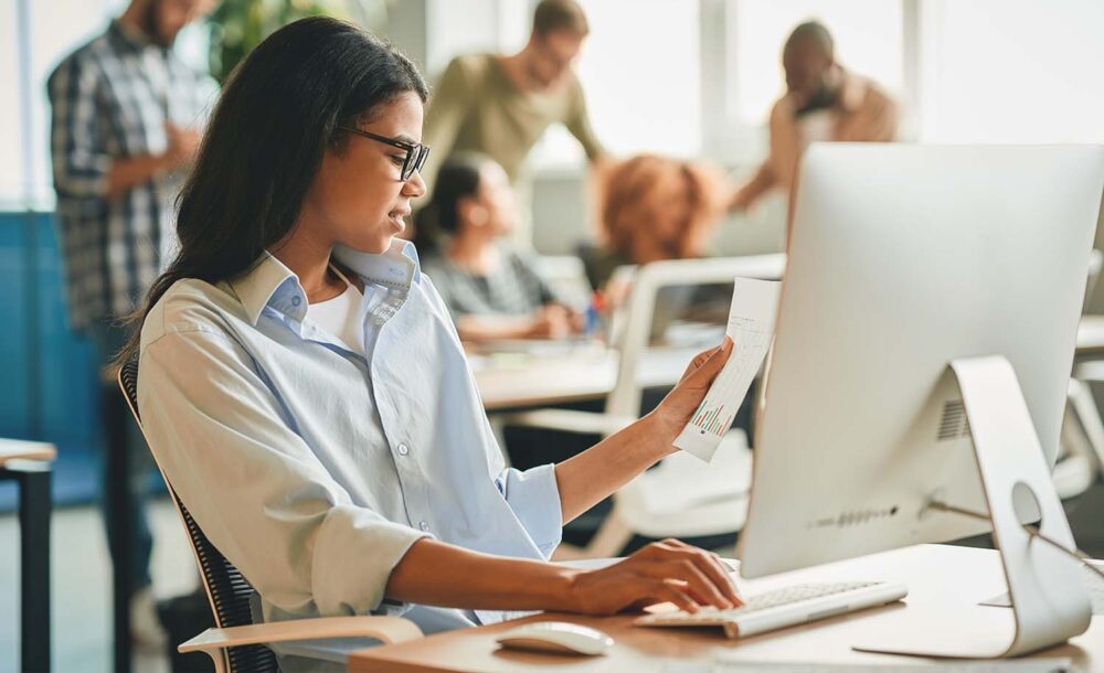 A young employee reviewing paperwork at a computer. Crucial compliance imagery for businesses navigating minor labor laws Utah regulations.