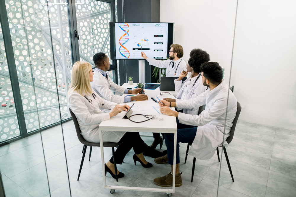 A medical team analyzing a DNA infographic display. Specialized life sciences recruiting firms focus on deep technical and genetic expertise.
