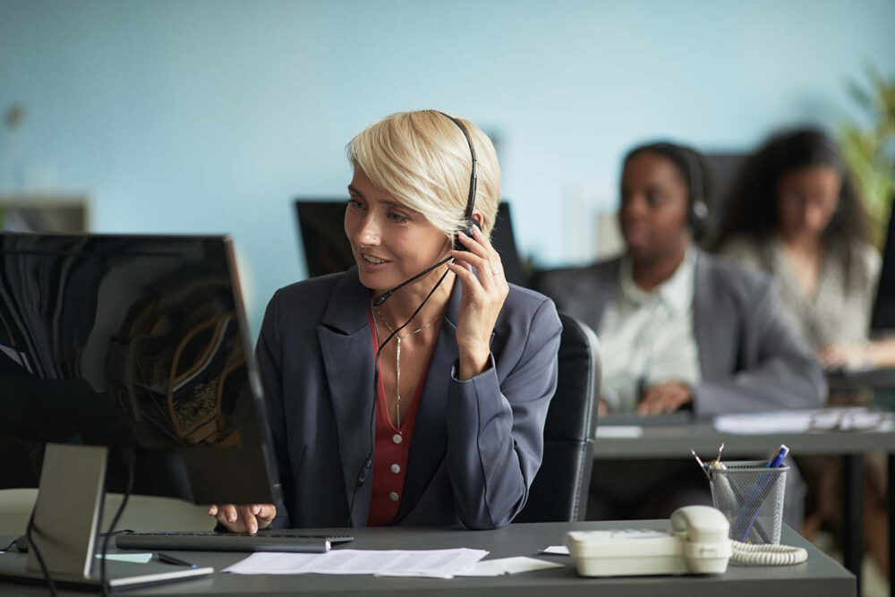 Customer support worker on a computer call, representing communication roles highly vulnerable to conversational automation and ai job loss.