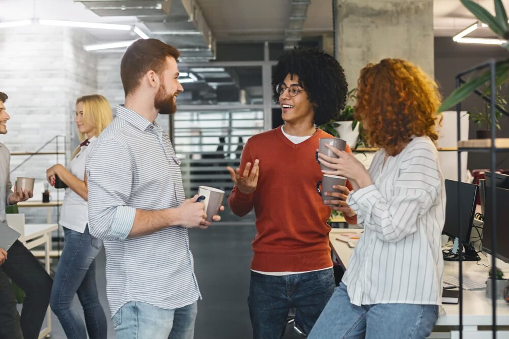 Young coworkers talking during an office break, illustrating a safe, non-hazardous work environment for youth and minors in utah.