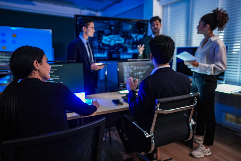 A team collaborating in a dark tech operations room, illustrating sectors heavily impacted by automated systems and ai job loss.