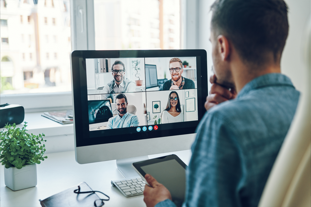 Hiring manager reviewing a four person video call while holding a tablet, reflecting how AI and recruiting technology streamline hiring